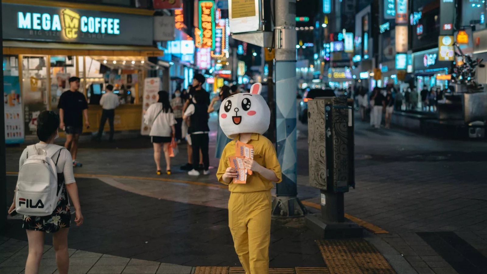 une mascotte de marque distribue des flyers dans la rue